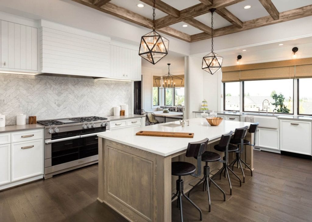Kitchen with wood ceiling beams, herringbone tile backsplash, island with pendant lights, and wood floor